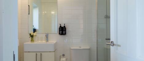 Un bagno con servizi igienici, lavandino, specchio e doccia.