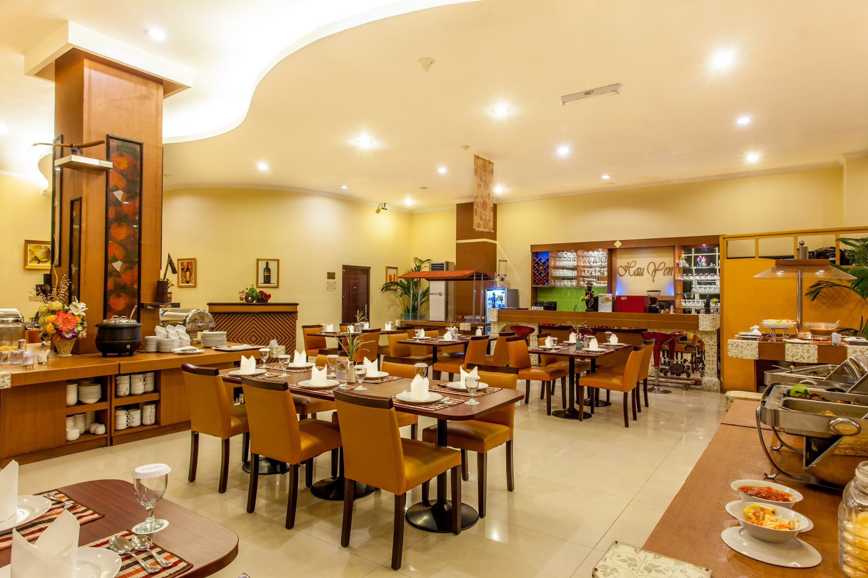 A restaurant with multiple dining tables and chairs, a buffet area, and a counter with various food items.