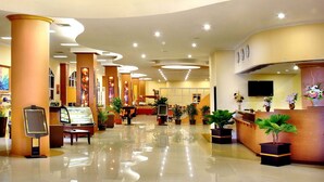 Rebost d'hotel amb taulell de recepció, zona de seients i plantes en testos.