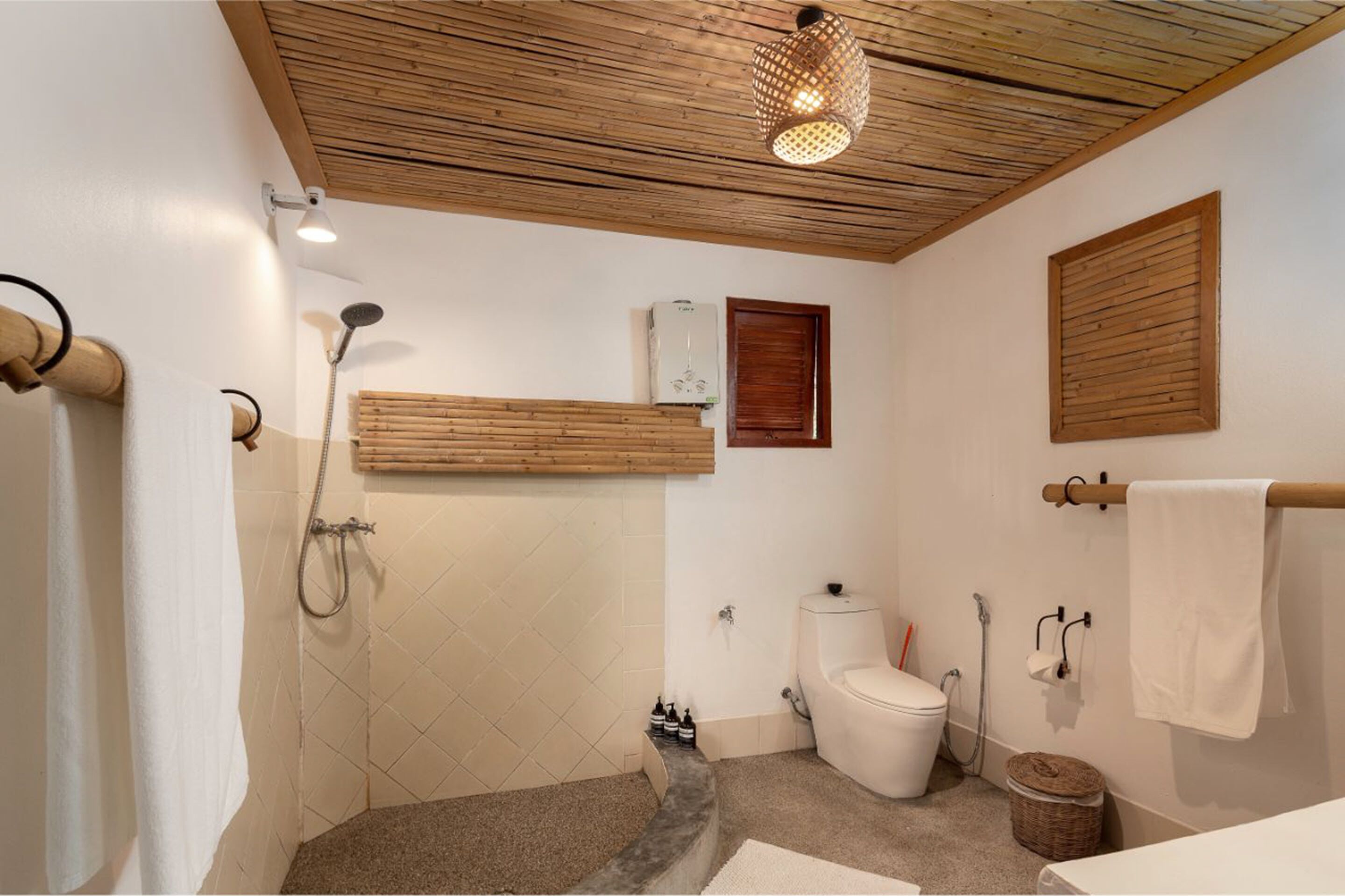 A bathroom with a shower, toilet, and a wooden ceiling.
