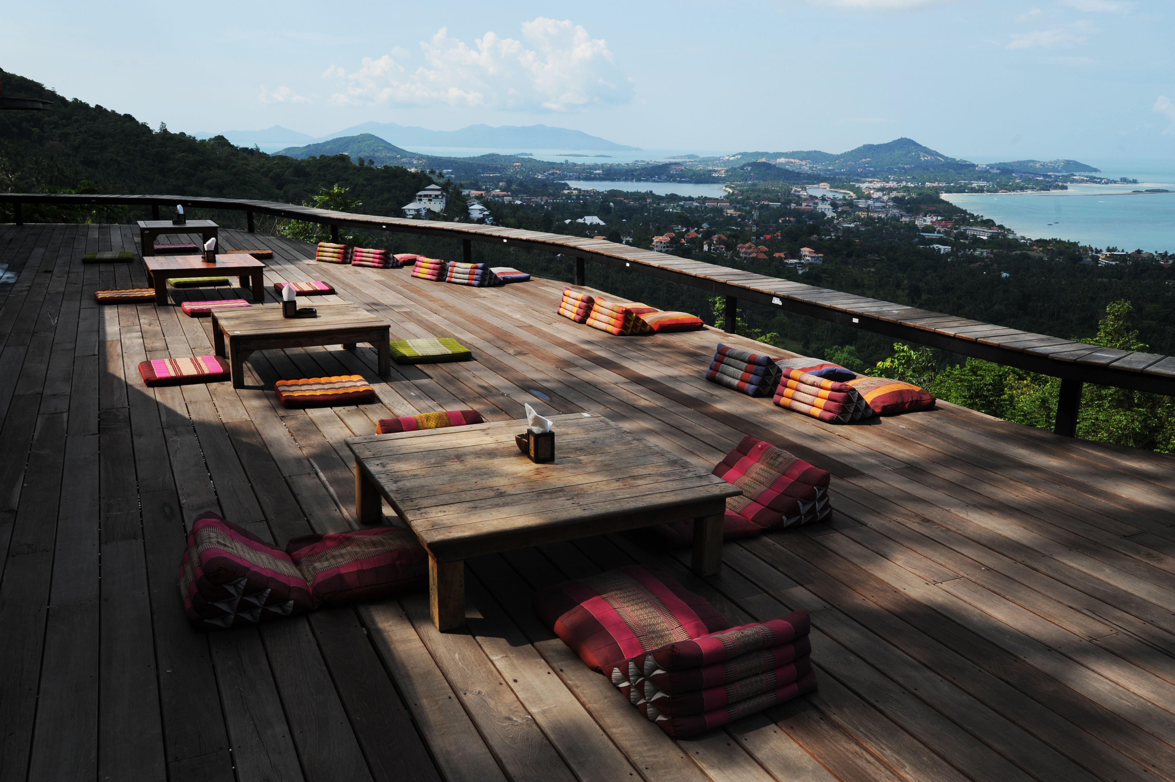 A wooden deck with seating and a view of a coastal landscape.