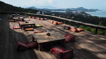 Una terraza de madera con asientos y vistas a un paisaje costero.