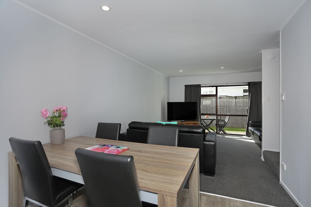 Una habitación moderna con una mesa de comedor, sillas, un televisor y un sofá.