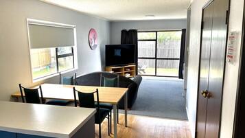 A compact living space with a kitchenette, dining area, and a TV.