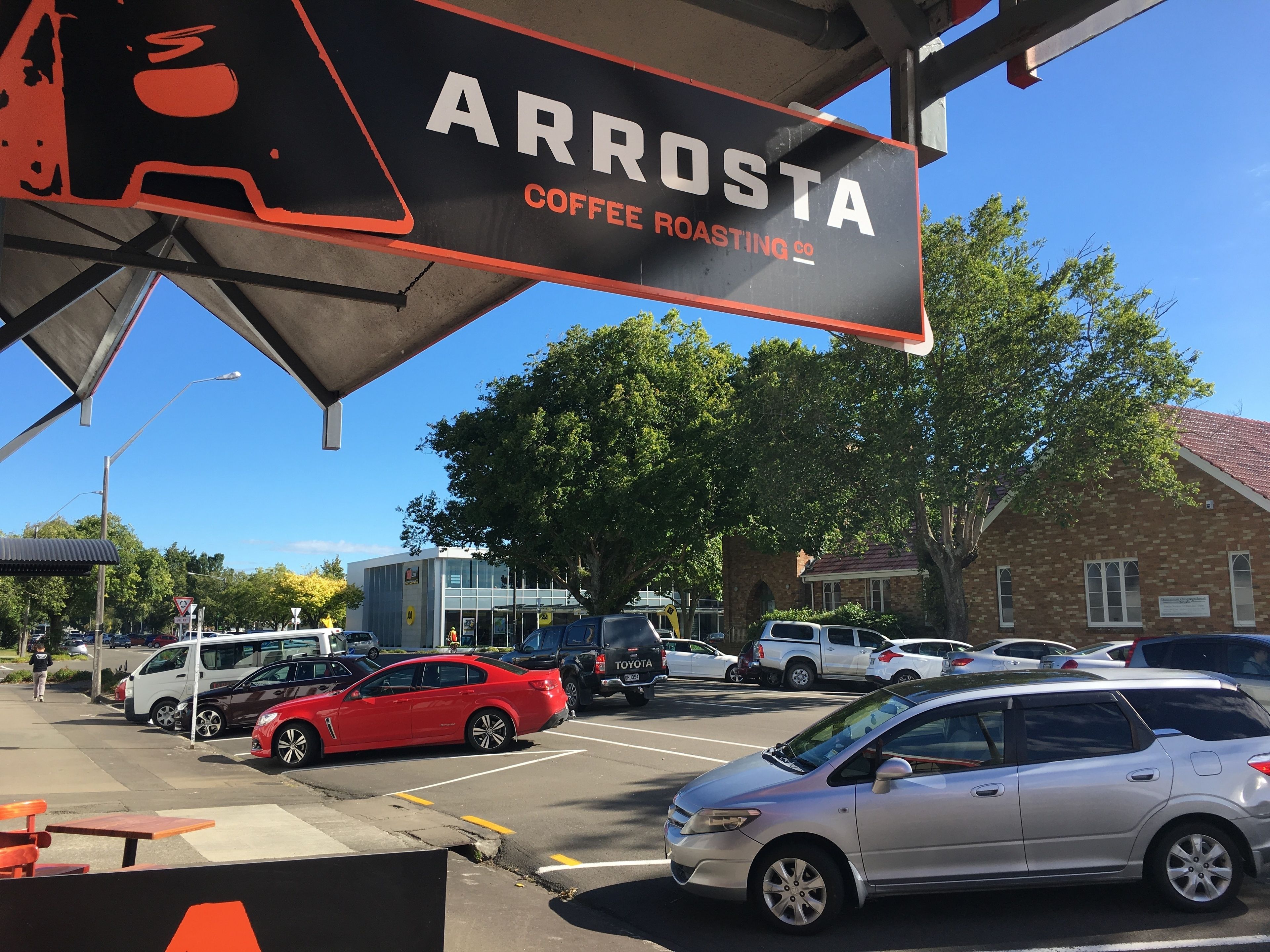 A parking lot with cars and a coffee roasting sign.
