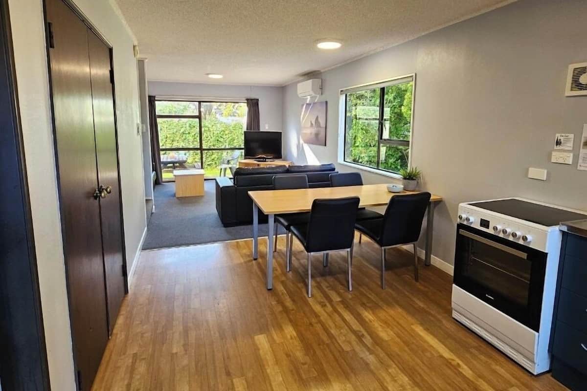 Una cocina moderna con comedor, suelo de madera y horno empotrado.