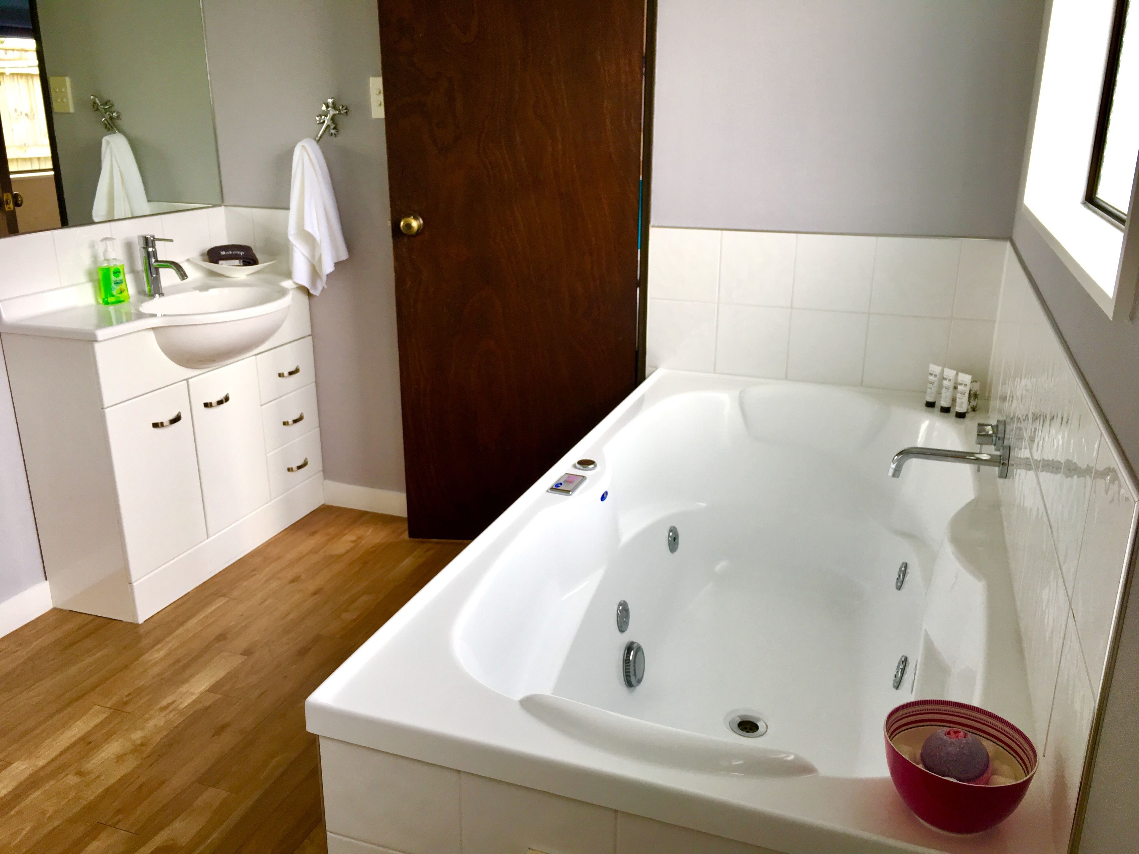 Un baño moderno con lavamanos, tocador y una bañera grande.