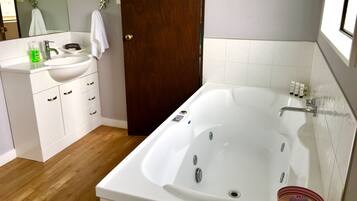 A modern bathroom with a white sink, vanity, and a large bathtub.