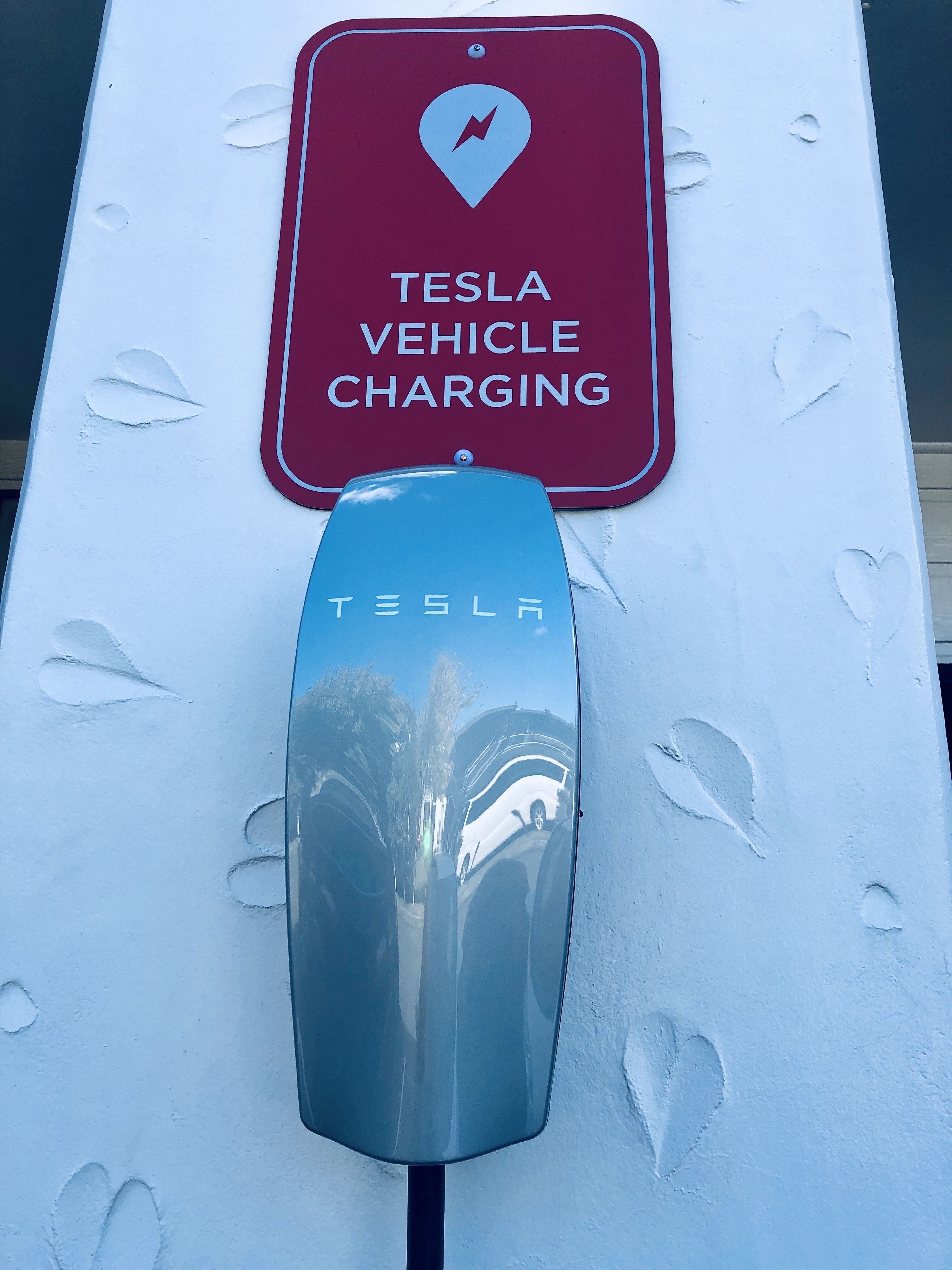 A Tesla vehicle charging station with a sign indicating "TESLA VEHICLE CHARGING".