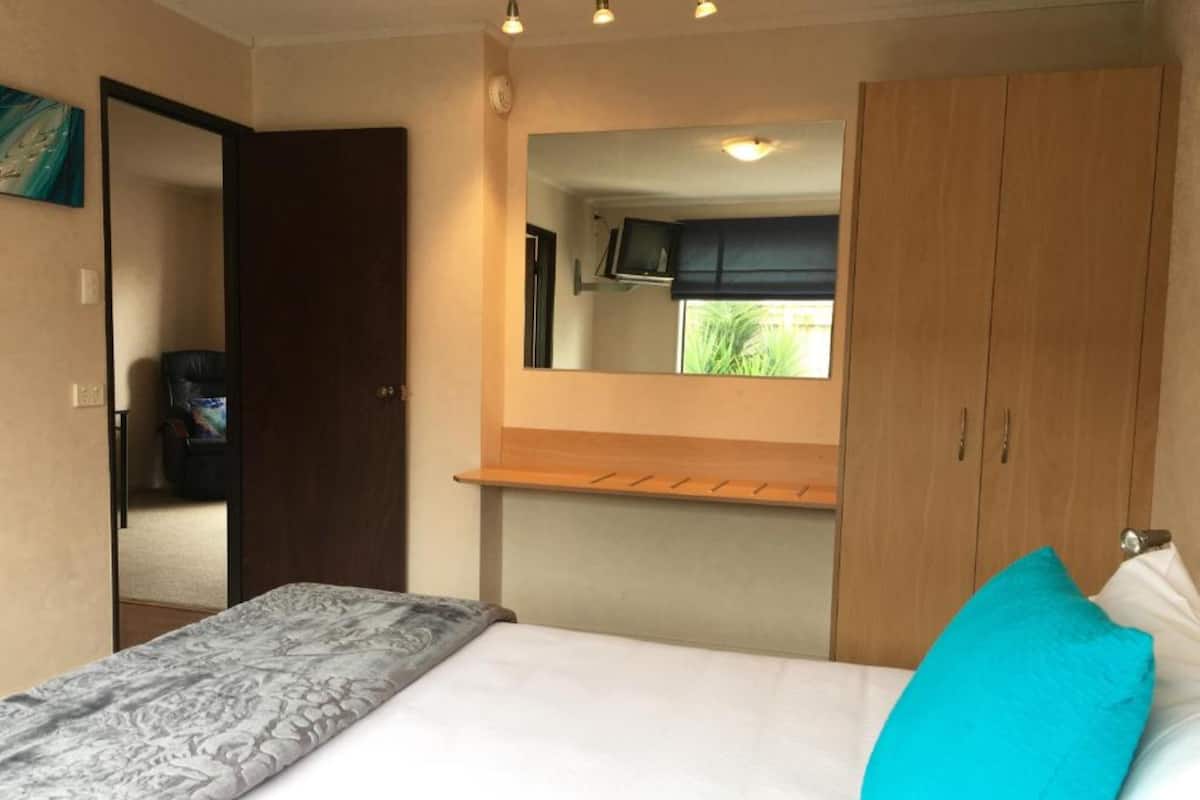 Un dormitorio con cama, espejo, armario y estante.