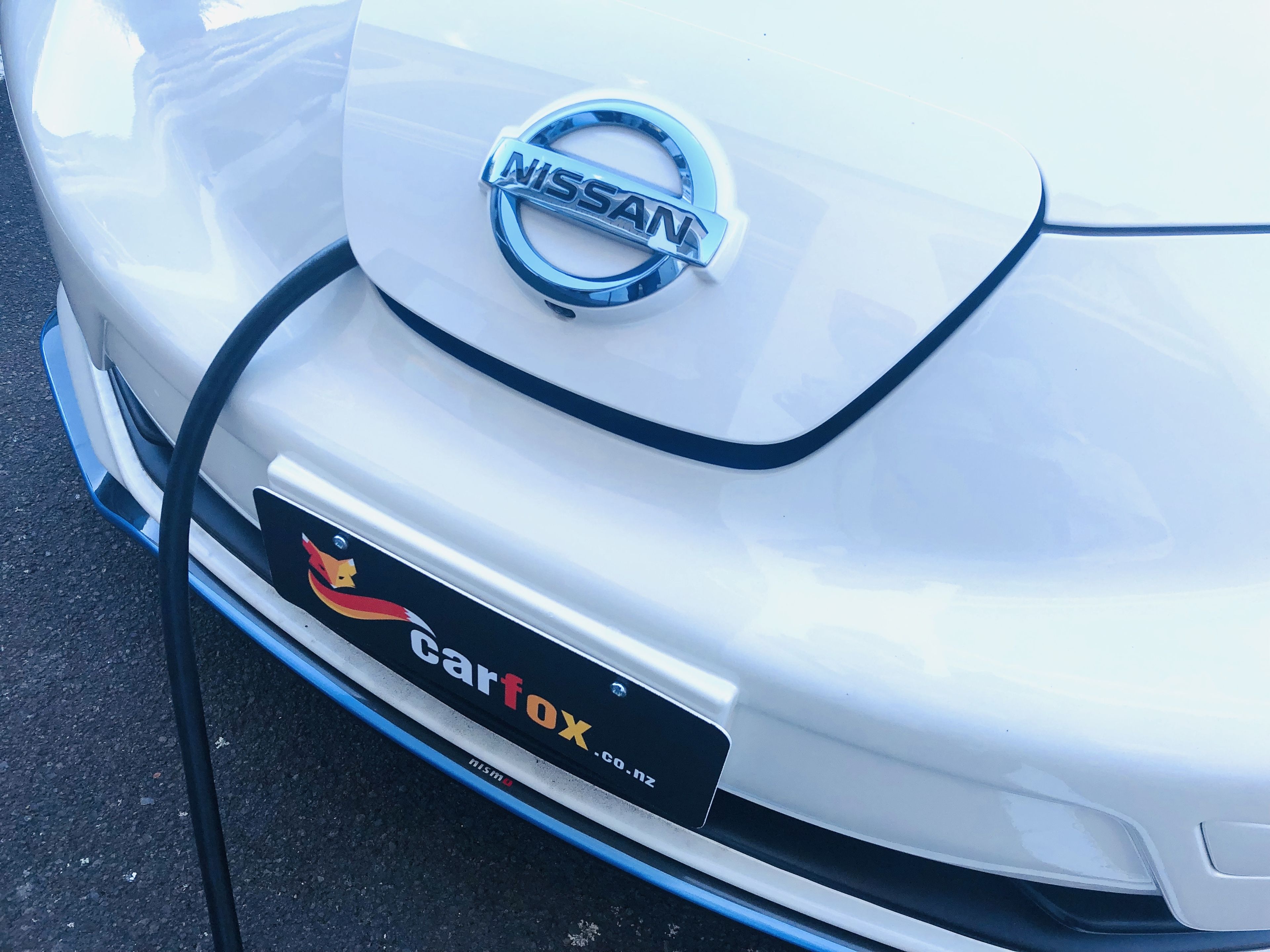 A white Nissan car with a 'Carfox' logo and a black license plate.