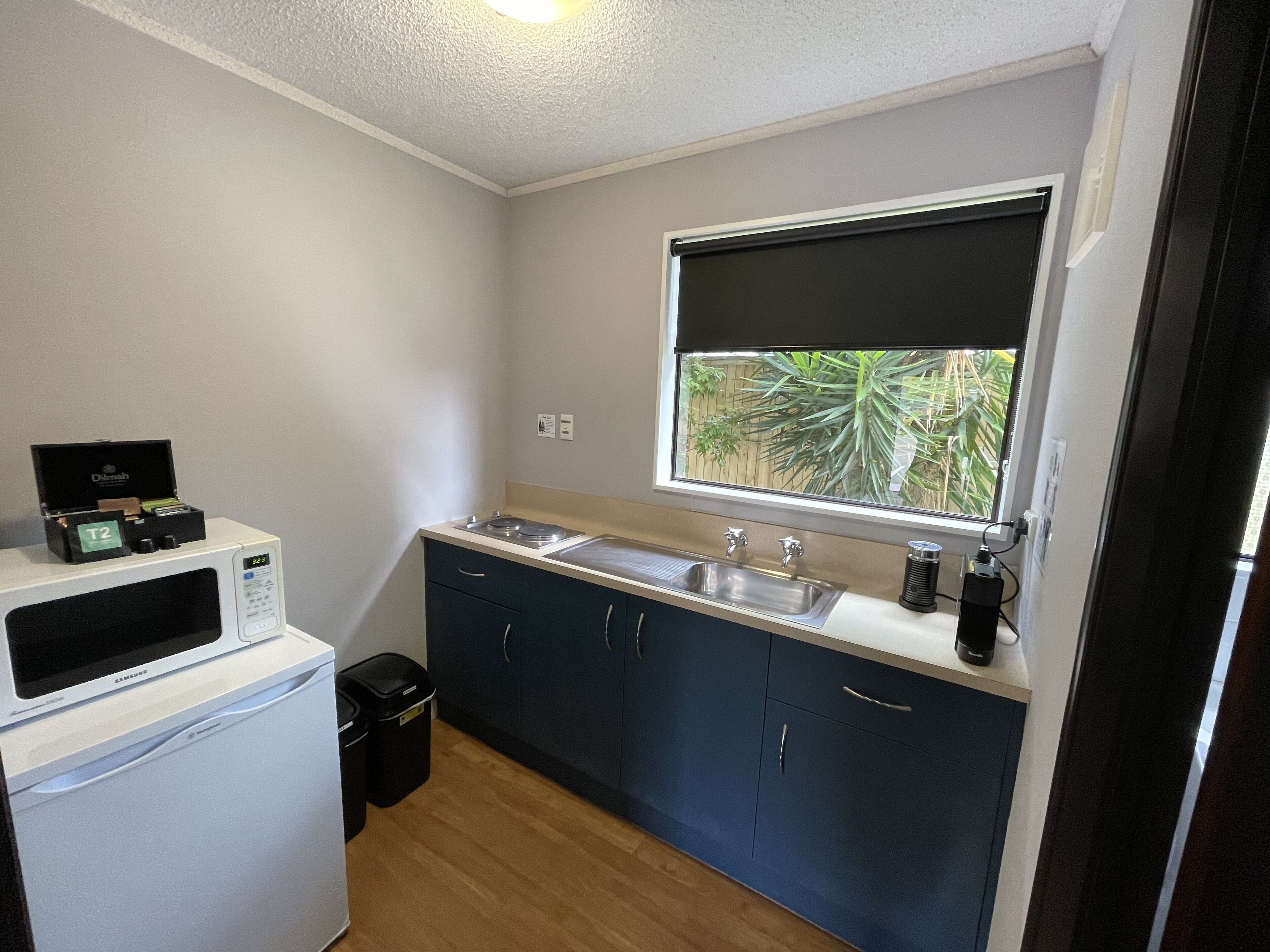 A compact kitchen with a microwave, sink, and cabinets.