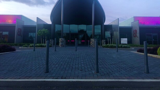 Un bâtiment moderne doté d’une conception architecturale unique, caractérisé par une façade centrale en verre et une entrée symétrique.