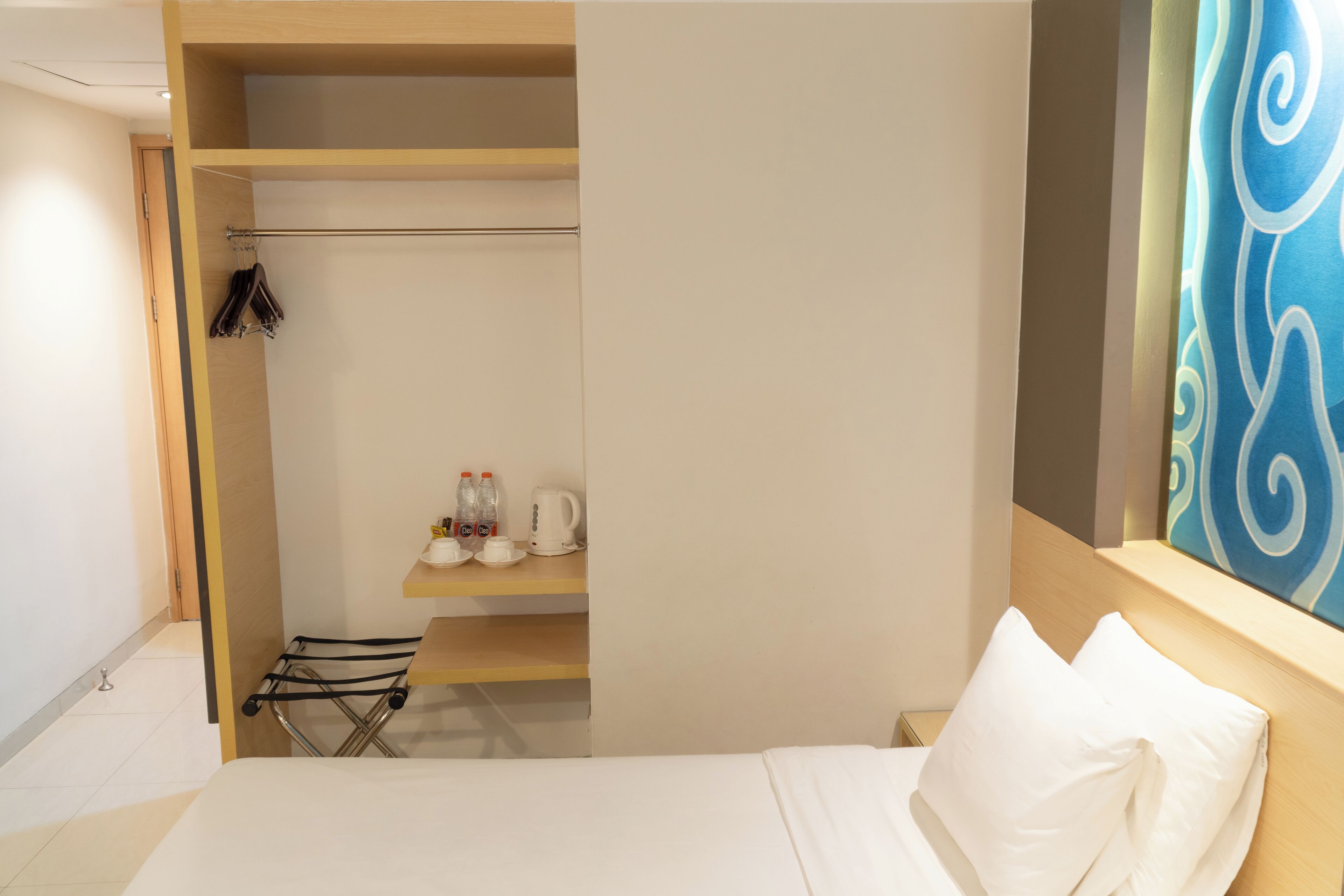 Ein Hotelzimmer mit Bett, Ablagefläche für Toilettenartikel und Blick auf den Flur.