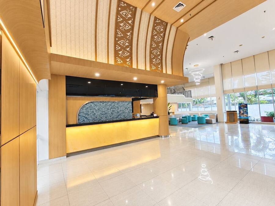 A modern hotel lobby with a reception desk, seating area, and large windows.
