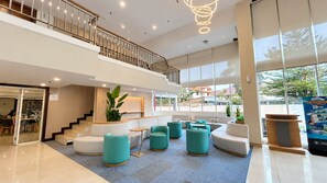 A spacious lobby with a staircase, seating area, and large windows. - Metland Hotel Cirebon (North Cirebon)