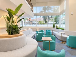 A modern lounge area with seating arrangements and large windows offering views of the outside.