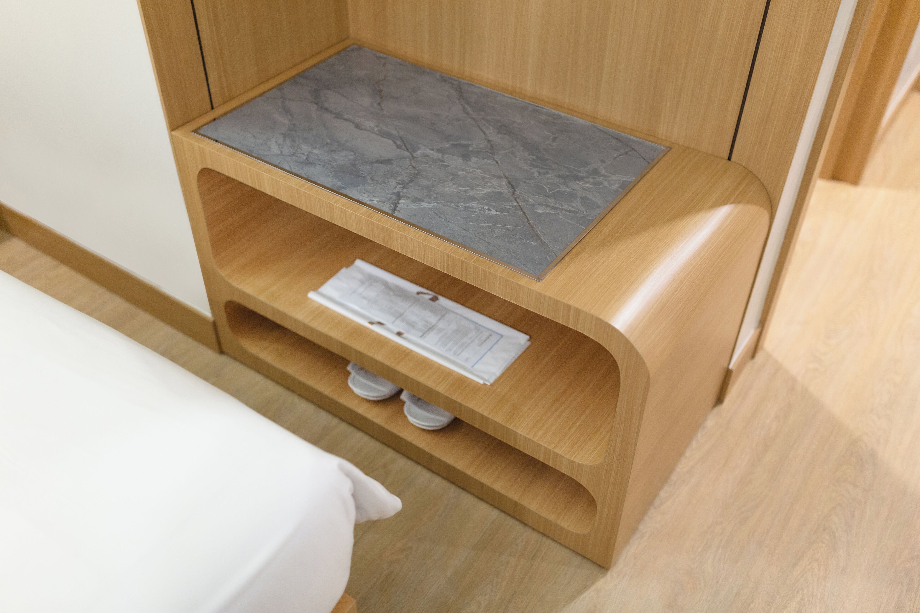 A wooden cabinet with a marble top shelf and a lower shelf with a white object.