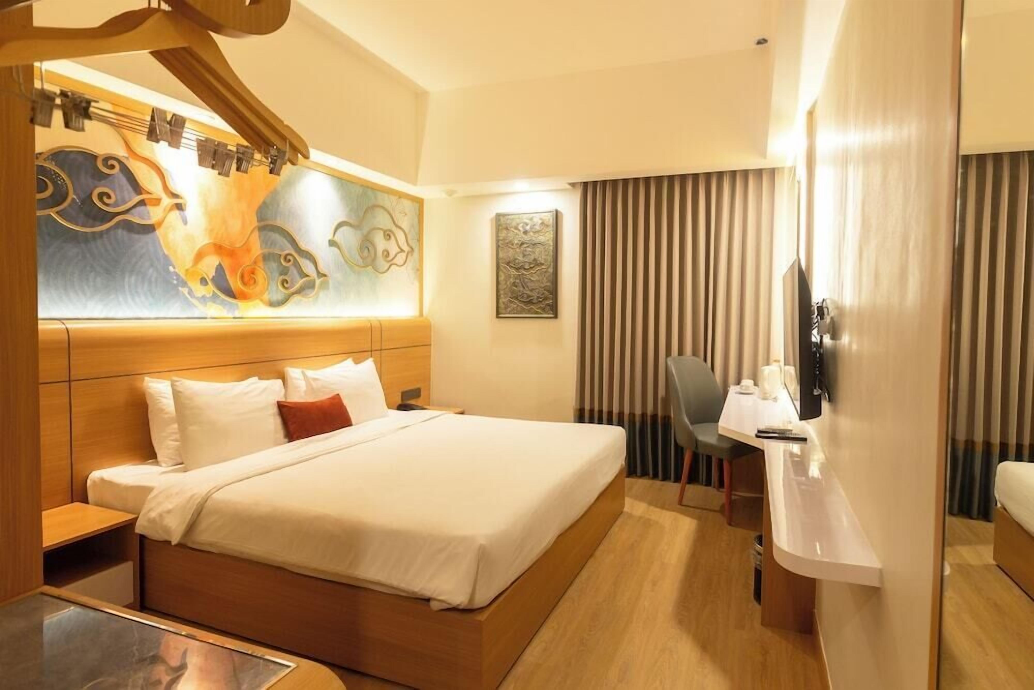 Une chambre d’hôtel avec un lit, une table de chevet, une chaise et une œuvre d’art au mur.