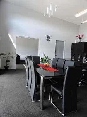 A modern conference room with a glass table, black chairs, and a red placemat.