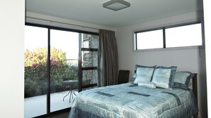 Un dormitorio con una cama grande, una ventana con vistas a la vegetación y una pared de piedra.