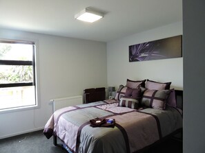 A bedroom with a bed, a radiator, a window, and a painting on the wall.