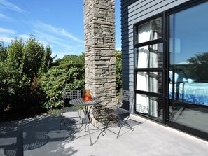 A patio with a stone pillar, a metal table, and two chairs.