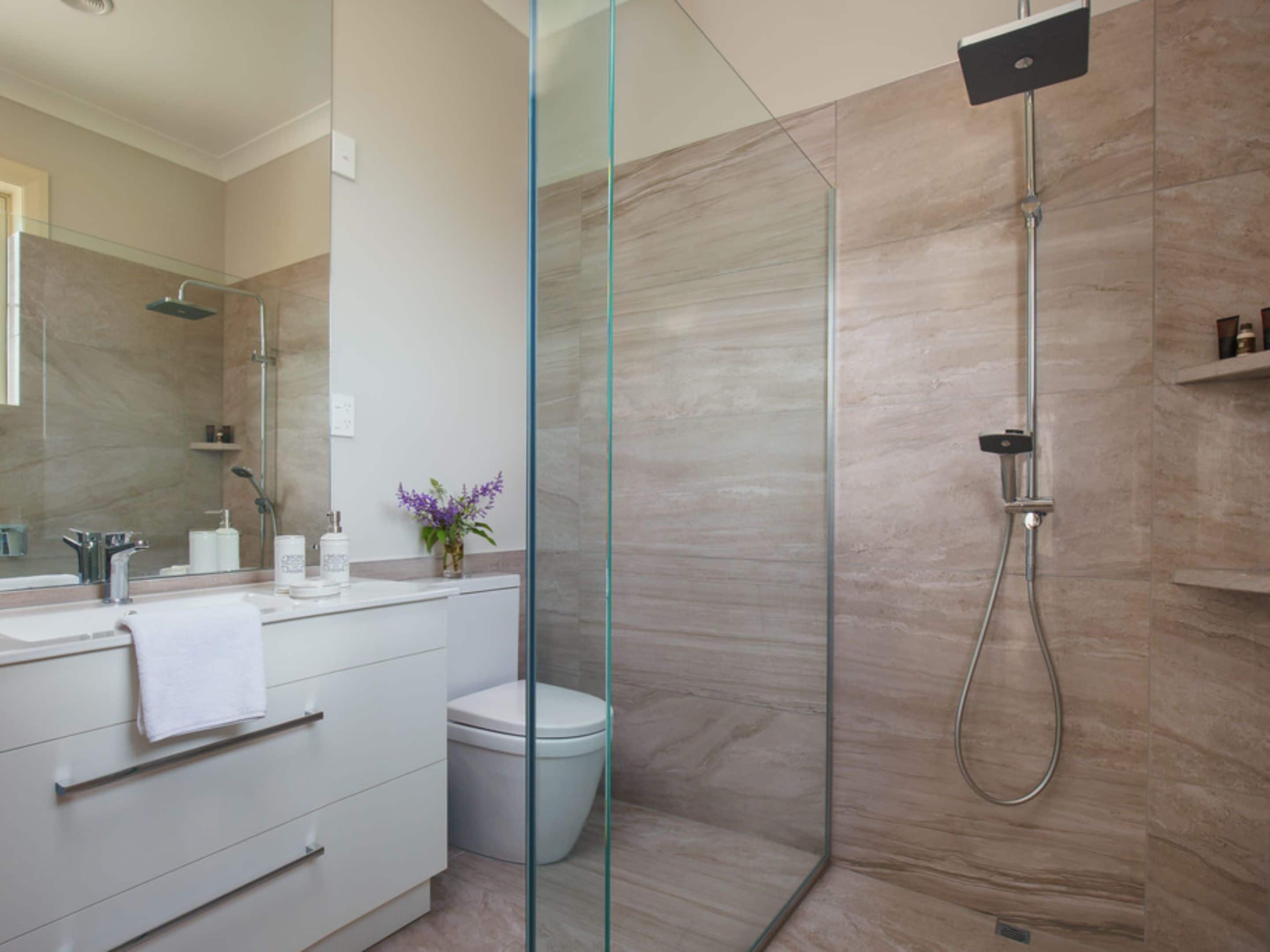 Un baño moderno con cabina de ducha de vidrio, un lavabo blanco y un inodoro.