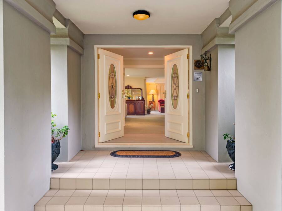 Un pasillo con dos puertas abiertas que dan a una habitación con una lámpara y un reloj.