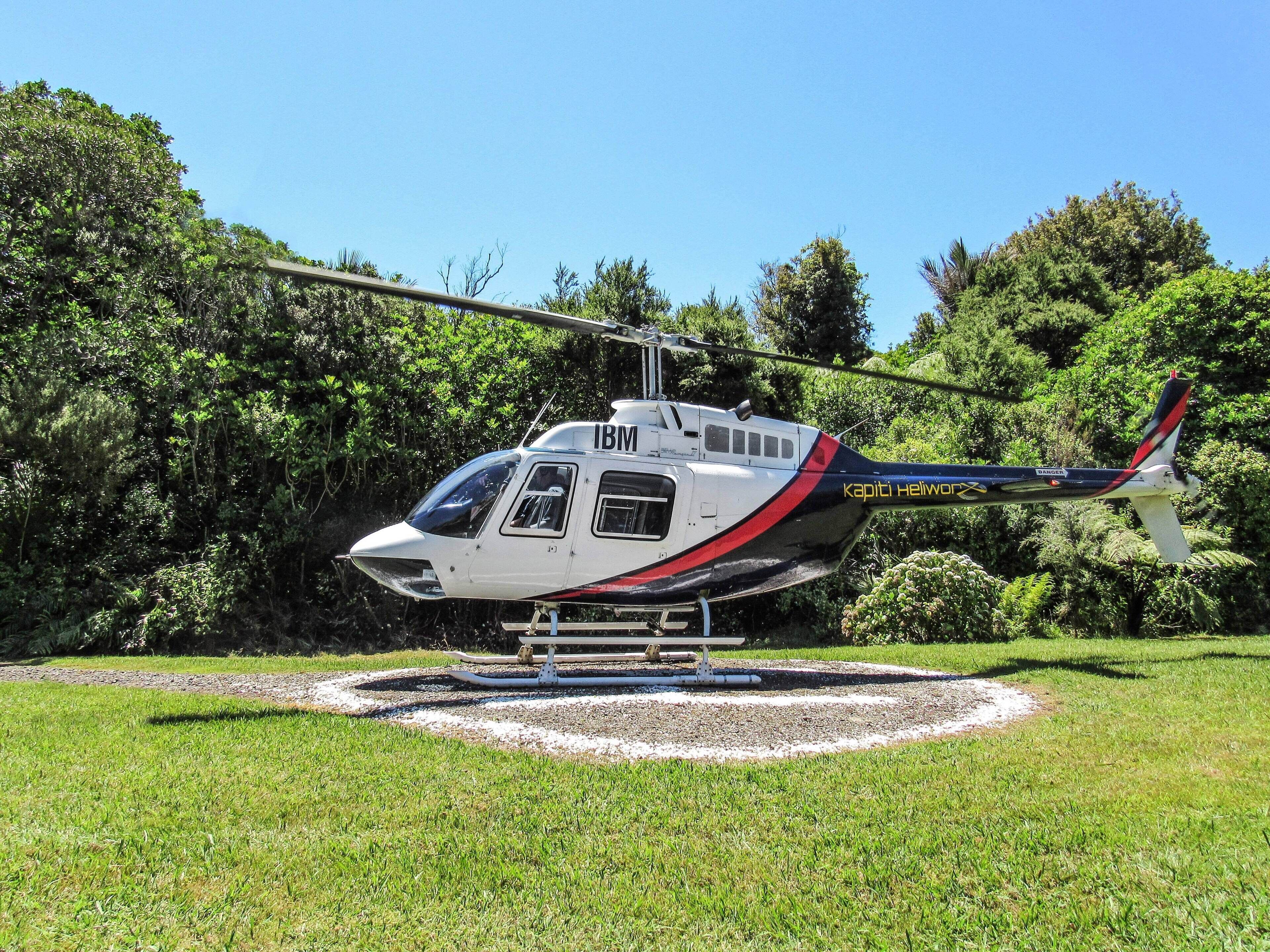A helicopter parked on a grassy area with a helipad in the center.