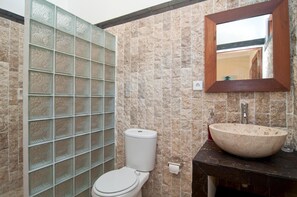 A bathroom with a toilet, a sink, and a mirror.
