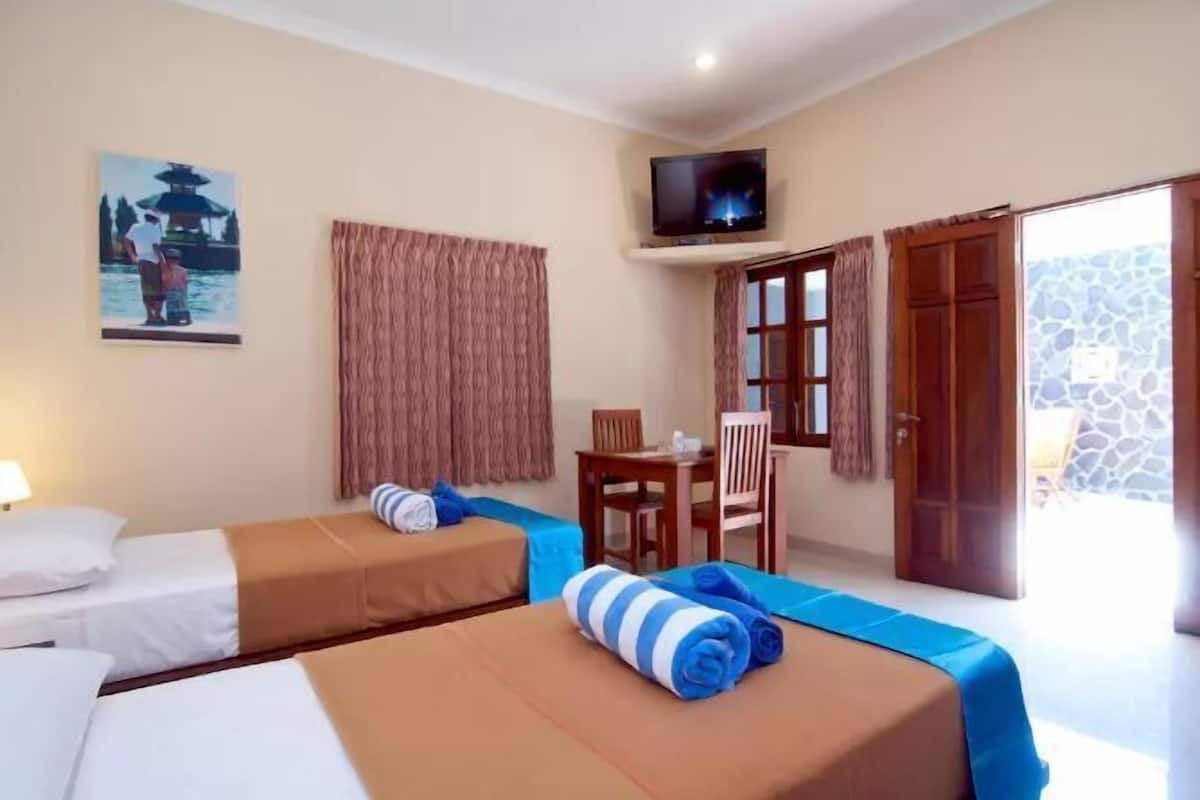 A hotel room with two beds, a television, a small table, and a chair.