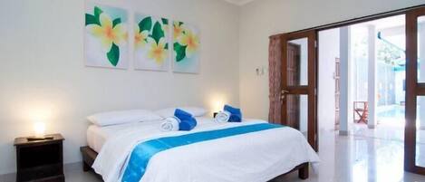 Un dormitorio con cama, mesita de noche y puerta que da a un balcón.
