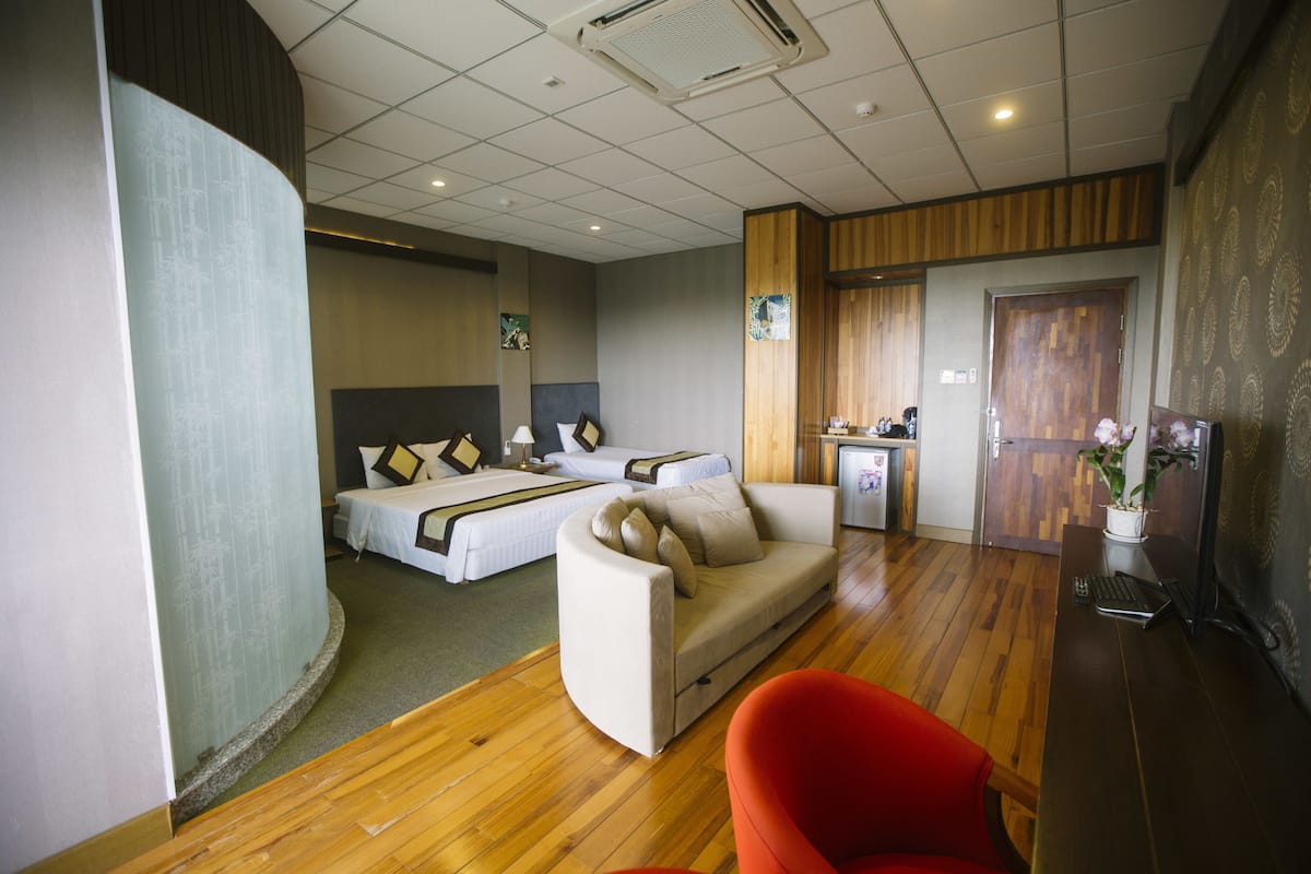 Ein Hotelzimmer mit zwei Betten, einem Sofa, einem Schreibtisch und einem roten Sessel.