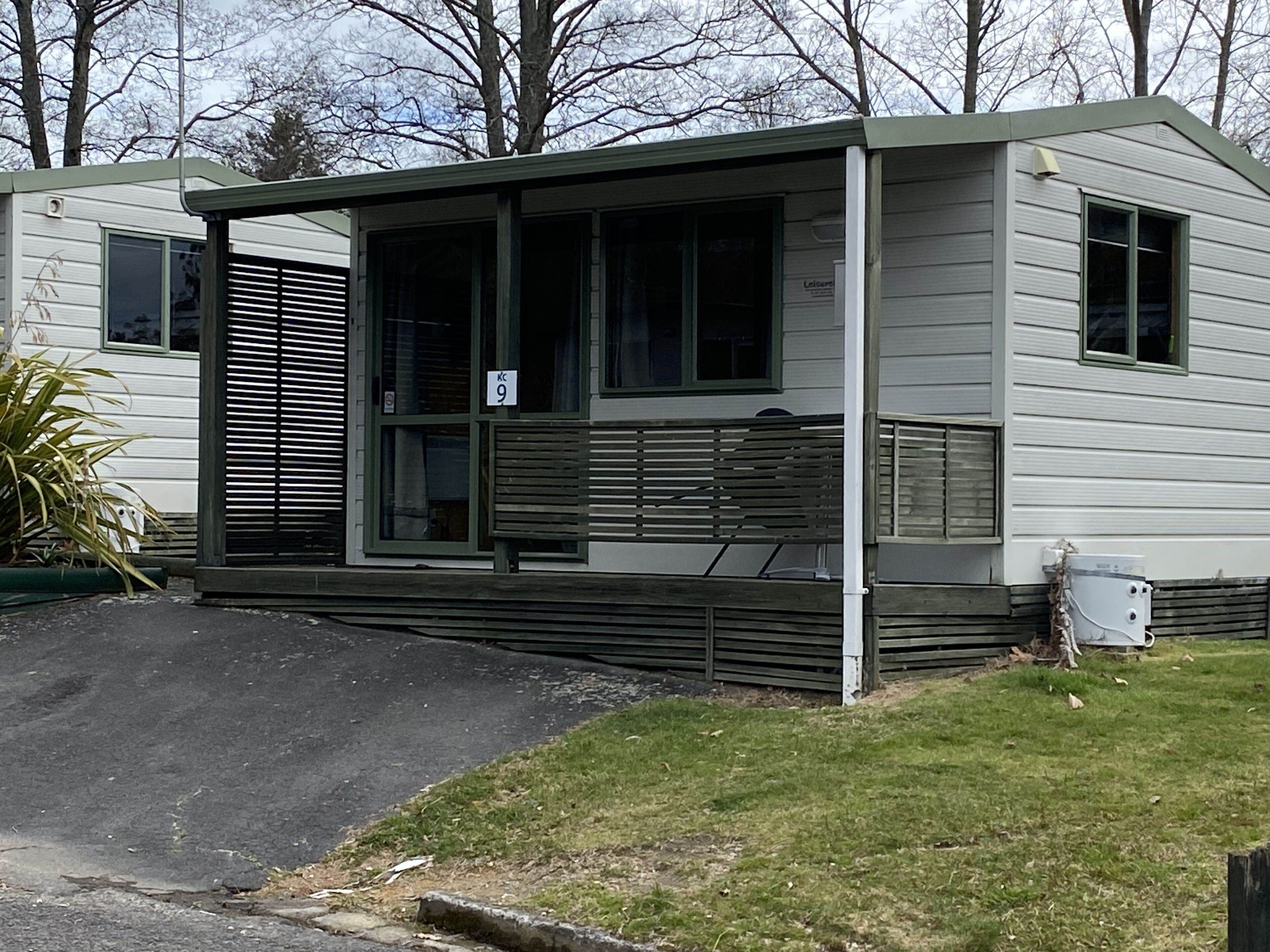 A mobile home with a covered porch, a small front yard, and a mailbox.
