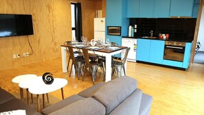 Un espacio habitable compacto con comedor, kitchenette y un sofá gris.