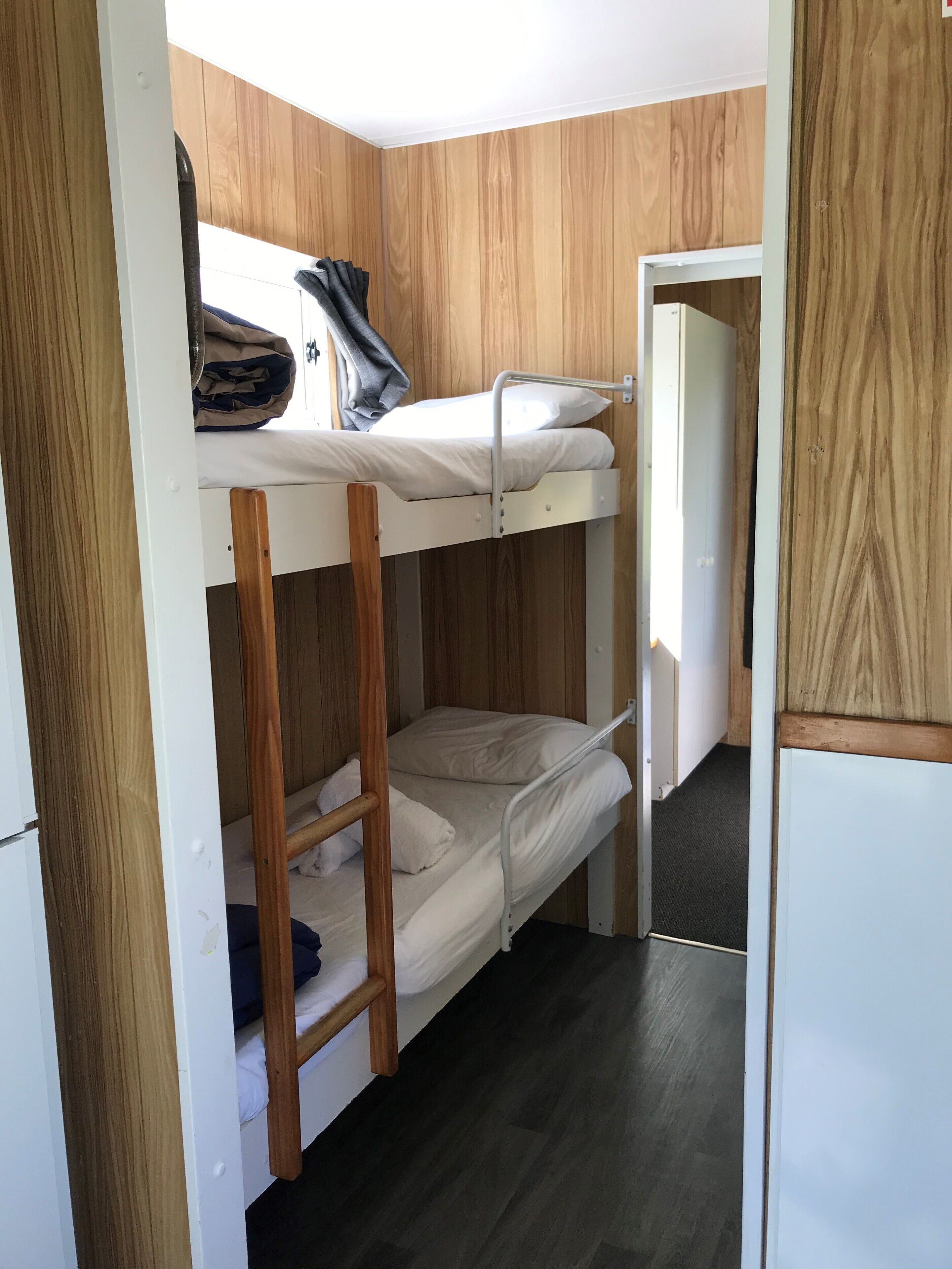 A bunk bed room with wooden paneling and a dark floor.