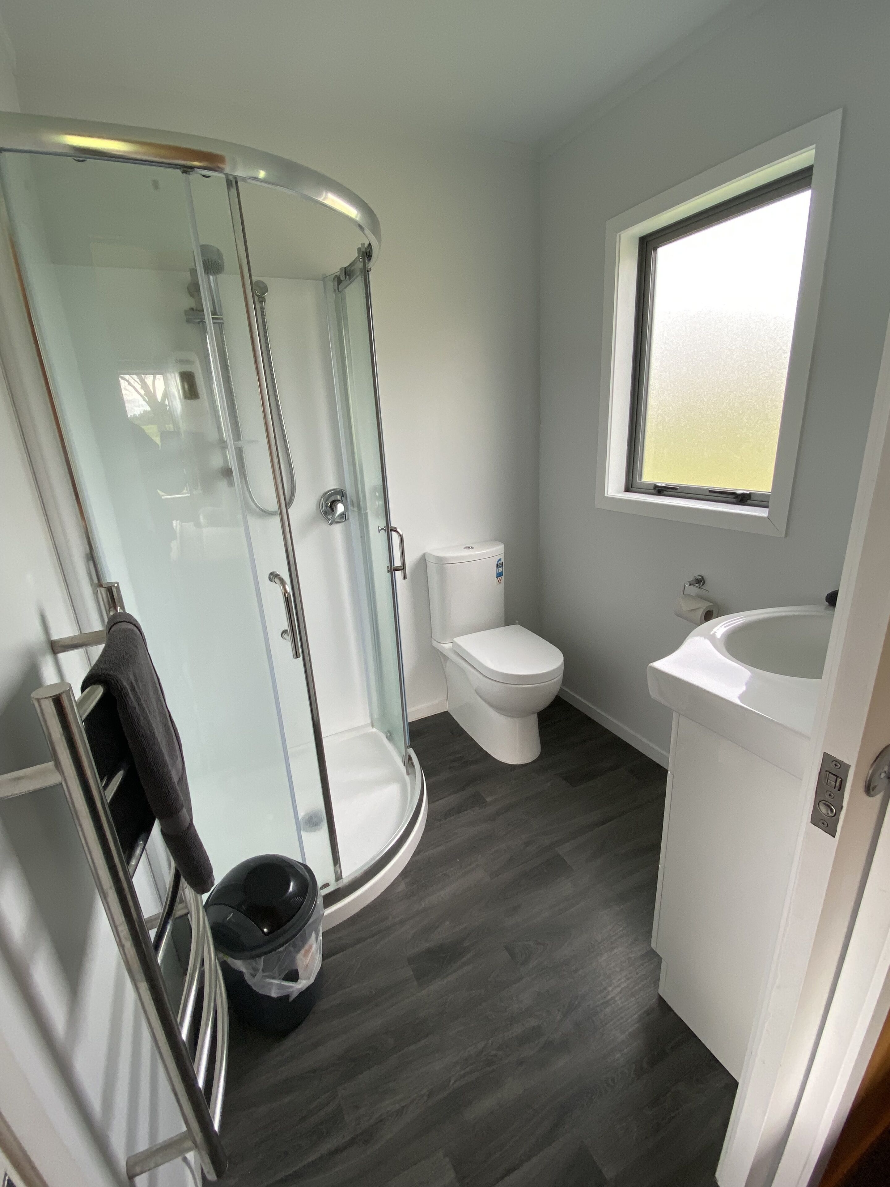 A bathroom with a glass-enclosed shower, a toilet, and a sink.