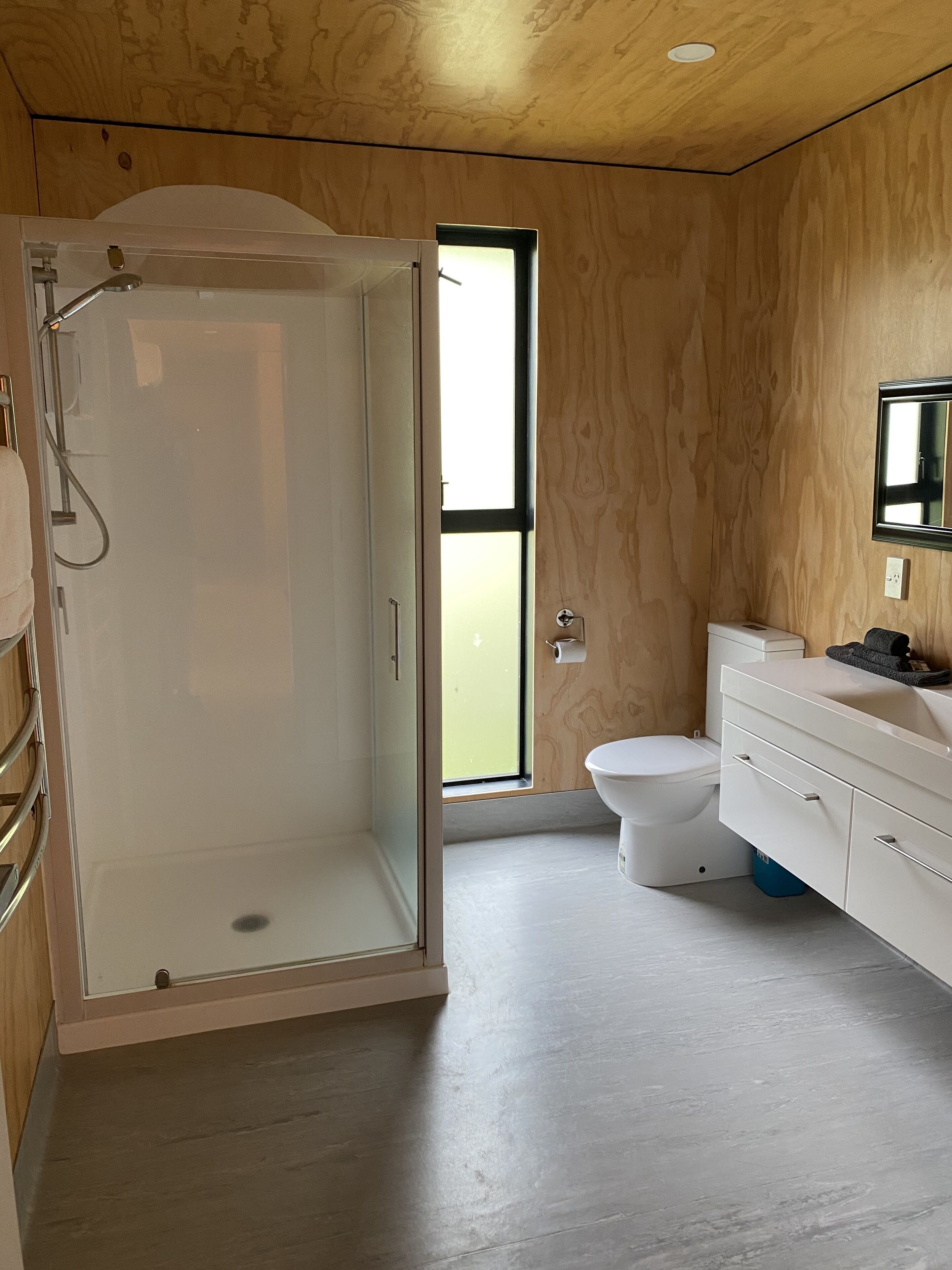 Une salle de bain moderne avec une douche à parois de verre, des toilettes et un meuble-lavabo avec des tiroirs.