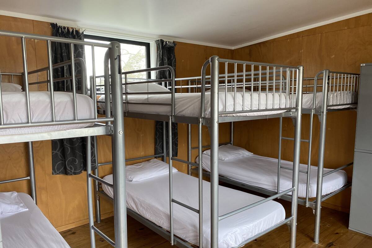 Une chambre avec un lit superposé, des murs en bois et une fenêtre avec des rideaux.