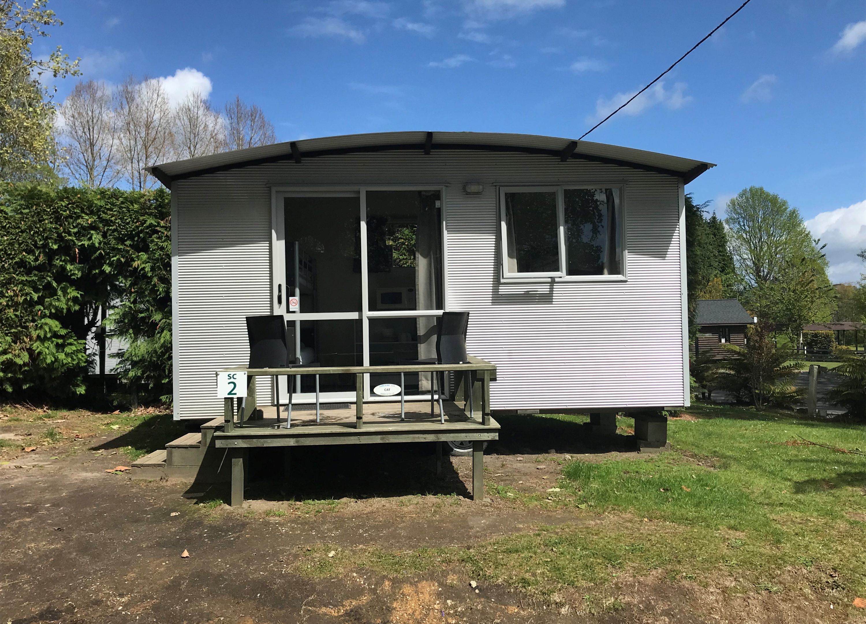 A small, single-story mobile home with a porch and a wheelchair-accessible ramp.
