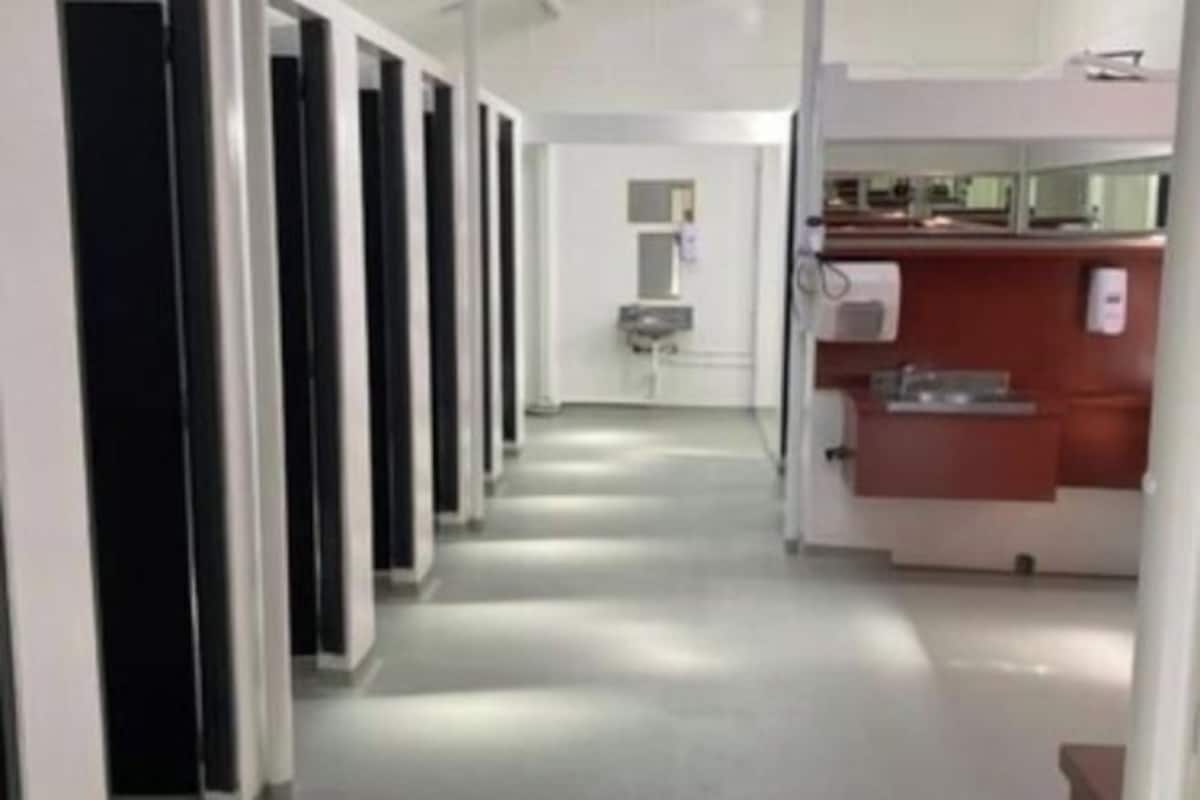 Un couloir bordé d’une série de pièces individuelles, chacune dotée d’une porte et d’une petite fenêtre.