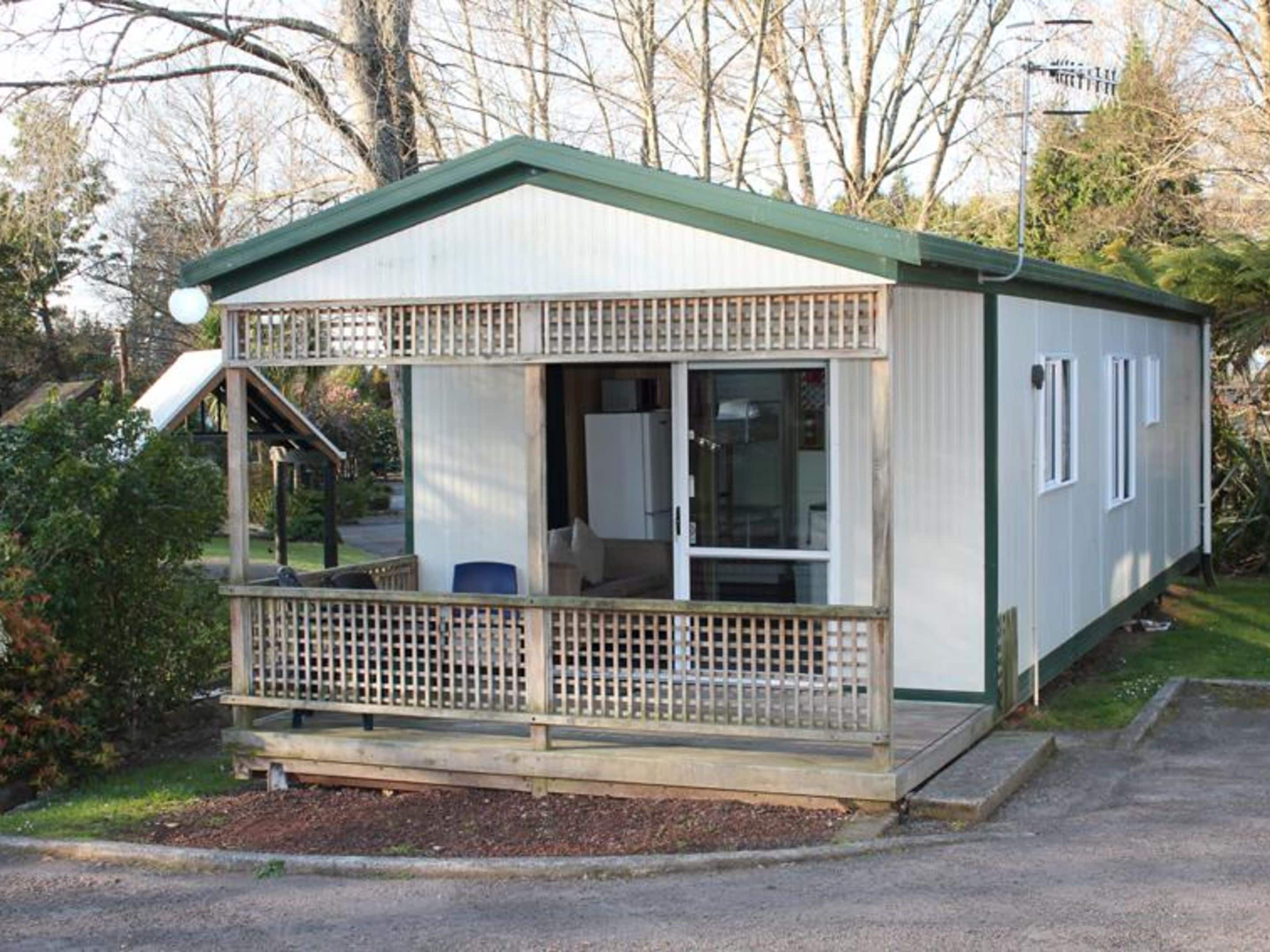 Une petite maison mobile de plain-pied, dotée d’une véranda et d’un espace extérieur abrité.