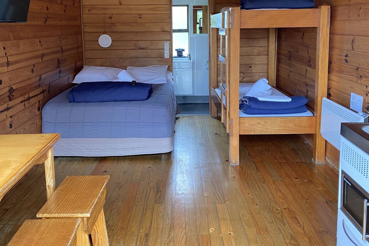 Un chalet confortable doté d’un lit en mezzanine, d’un canapé-lit, d’une table à manger et d’une petite cuisine.