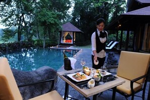 Mesa de comedor al aire libre con vista a una piscina y un pabellón al fondo.