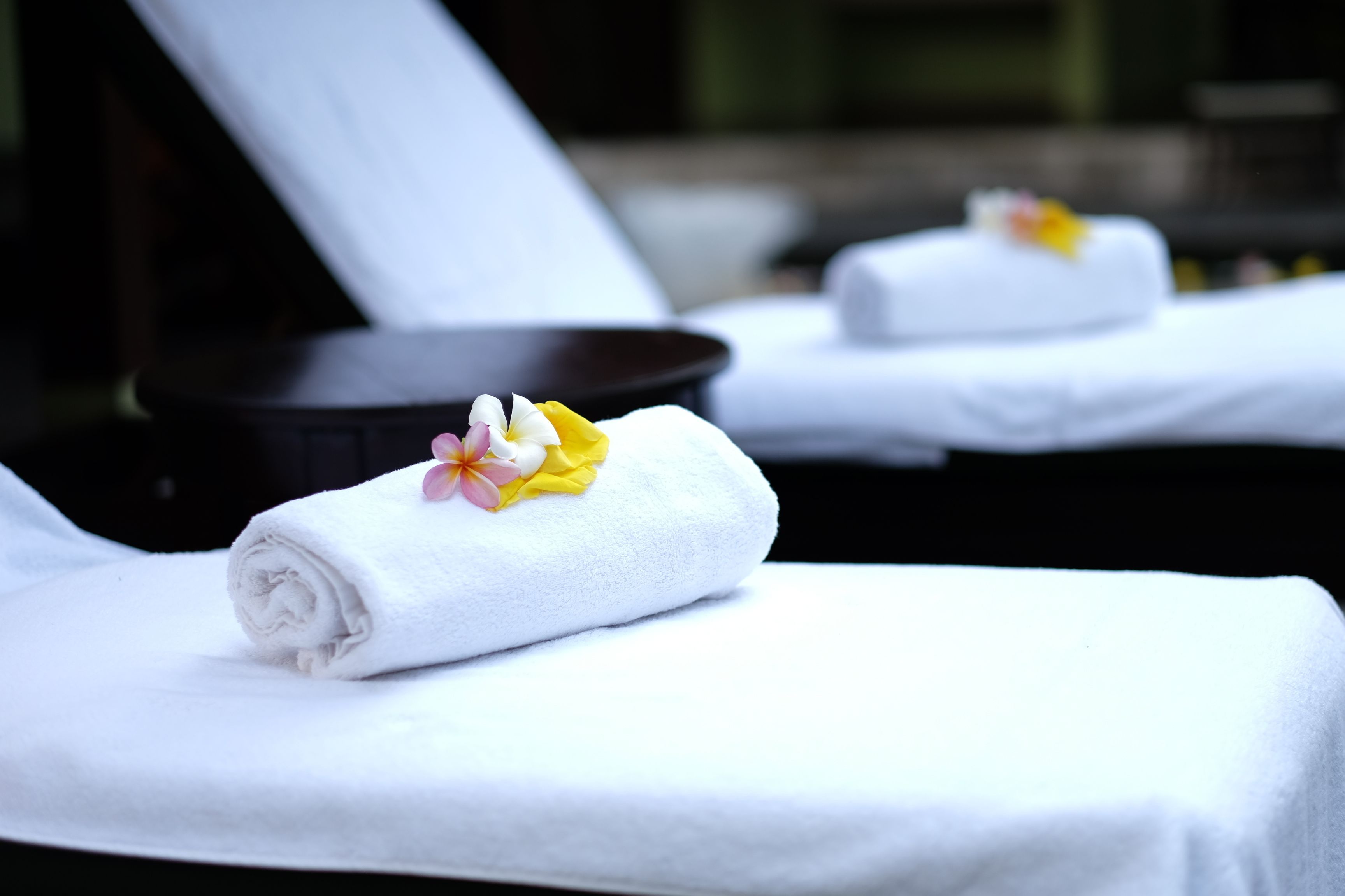 Zona de spa con toallas blancas y una decoración floral en una tumbona.