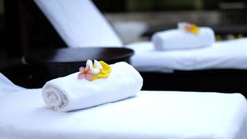 Zona de spa con toallas blancas y una decoración floral en una tumbona.