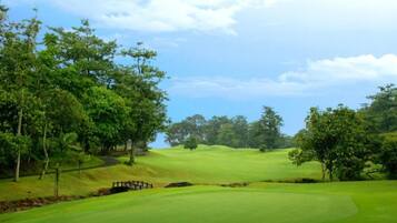 Un campo de golf con un fairway cuidado, bunkers de arena y un puente de madera.