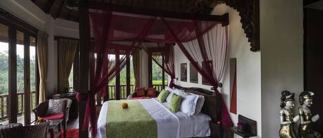 Um quarto espaçoso com uma cama grande, um espaço de estar com uma poltrona e vista para o exterior.