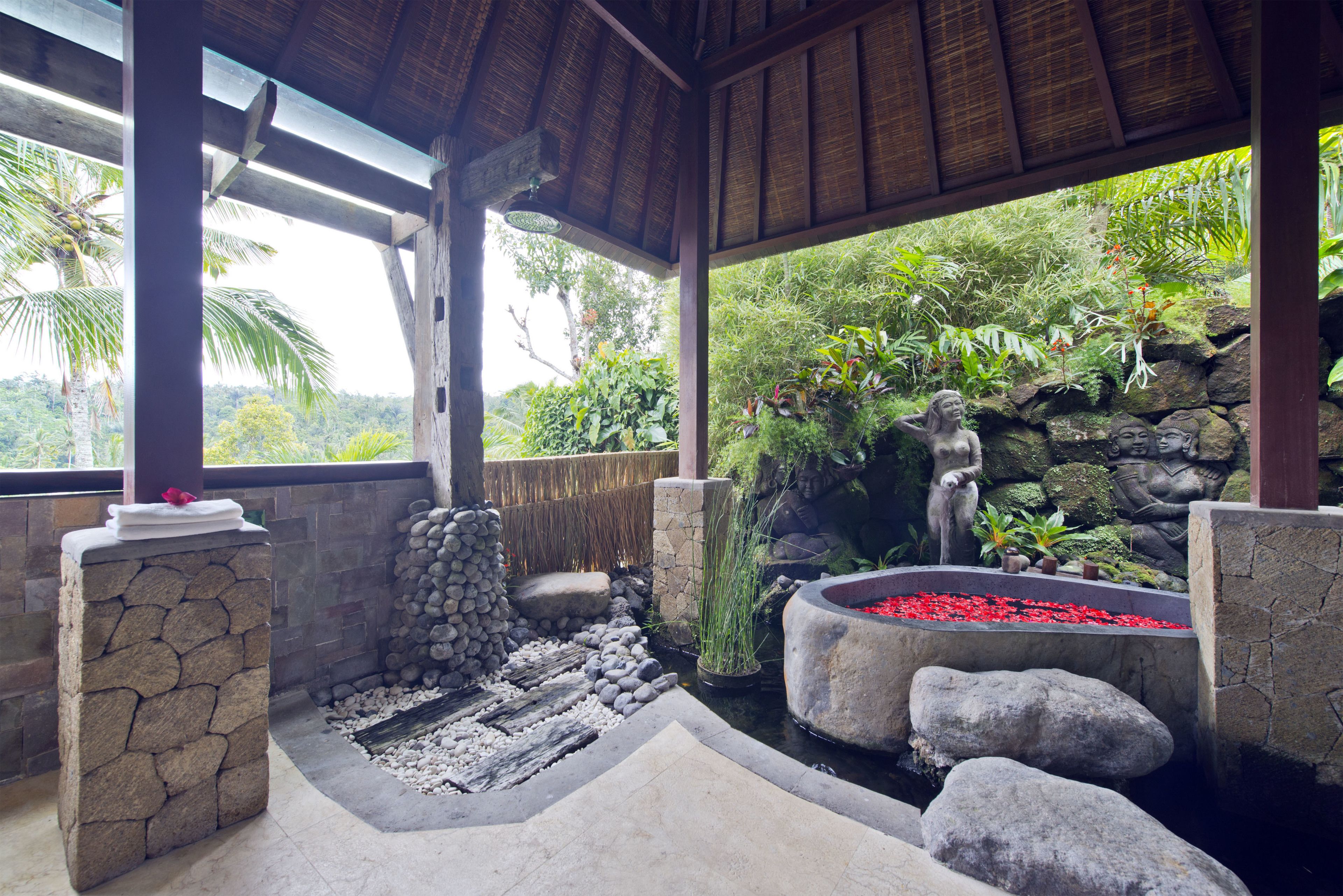 A covered outdoor area with stone walls, a small water feature, and tropical plants.